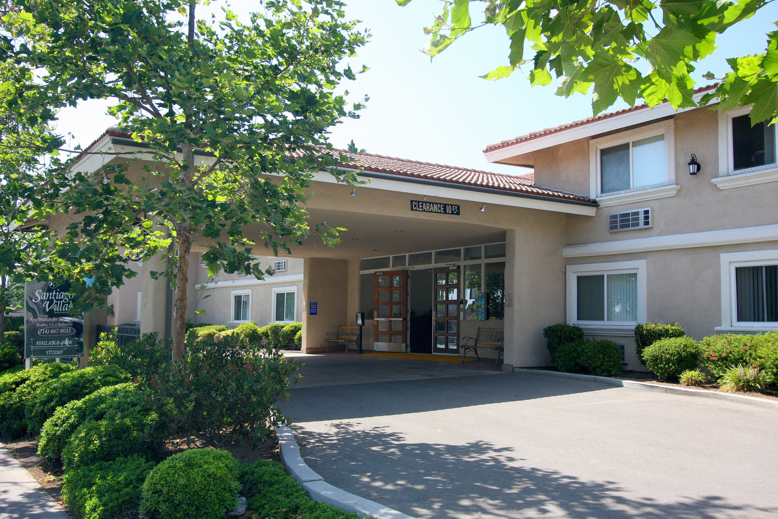 Santiago Villas in Santa Ana: the covered entry and drop-off of the senior community, framed by trees